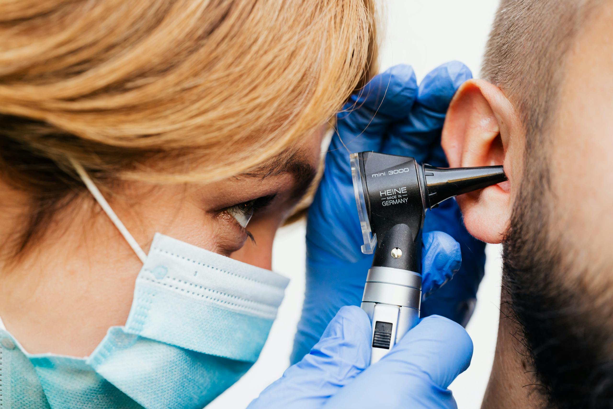 Close-up of a doctor performing an ear examination with an otoscope.